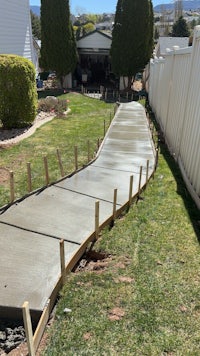 a concrete walkway is being built in a backyard